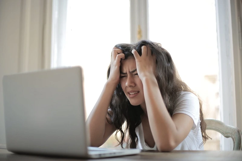 Young woman experiencing anxiety and emotional distress while using a laptop, representing professional anxiety therapy and psychological counseling services in Lahore.