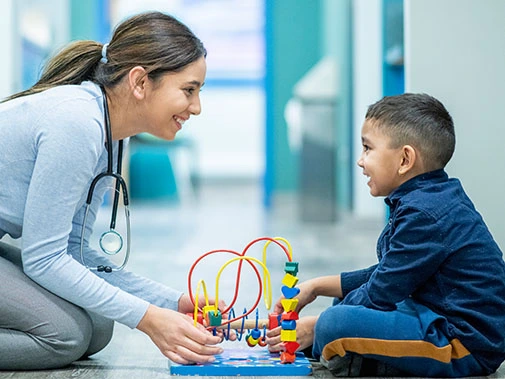 Occupational therapist working one-on-one with a child using educational toys to improve fine motor skills, sensory integration, coordination, and cognitive development at Care & Cure Wellness Center in Lahore.