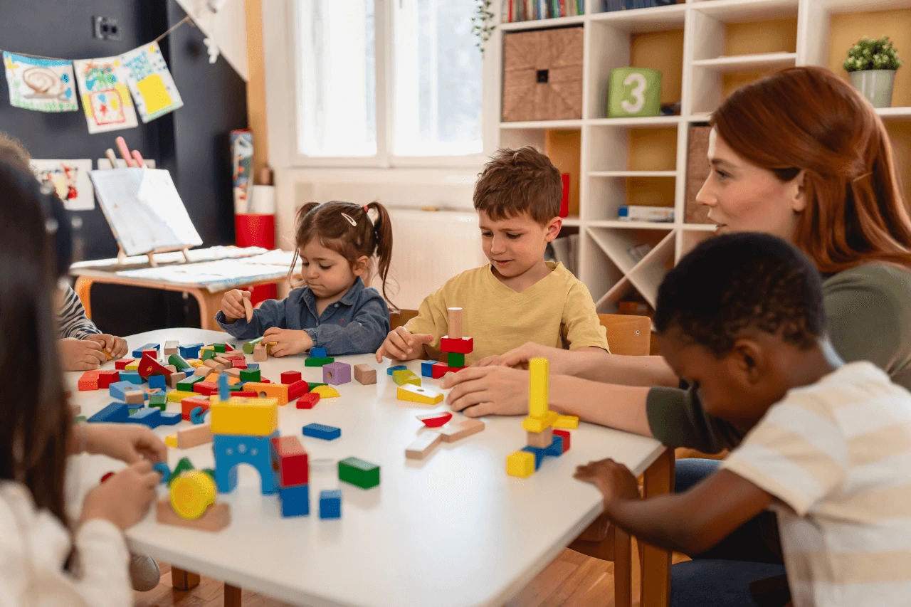 Children participating in a school readiness program with an early childhood educator, developing cognitive, social, communication, fine motor, and classroom readiness skills through interactive learning activities at Care & Cure Wellness Center in Lahore.