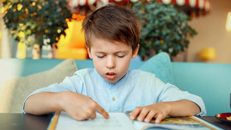 Young slow learner child receiving individualized educational support while practicing reading and learning skills through a personalized learning program at Care & Cure Wellness Center in Lahore.