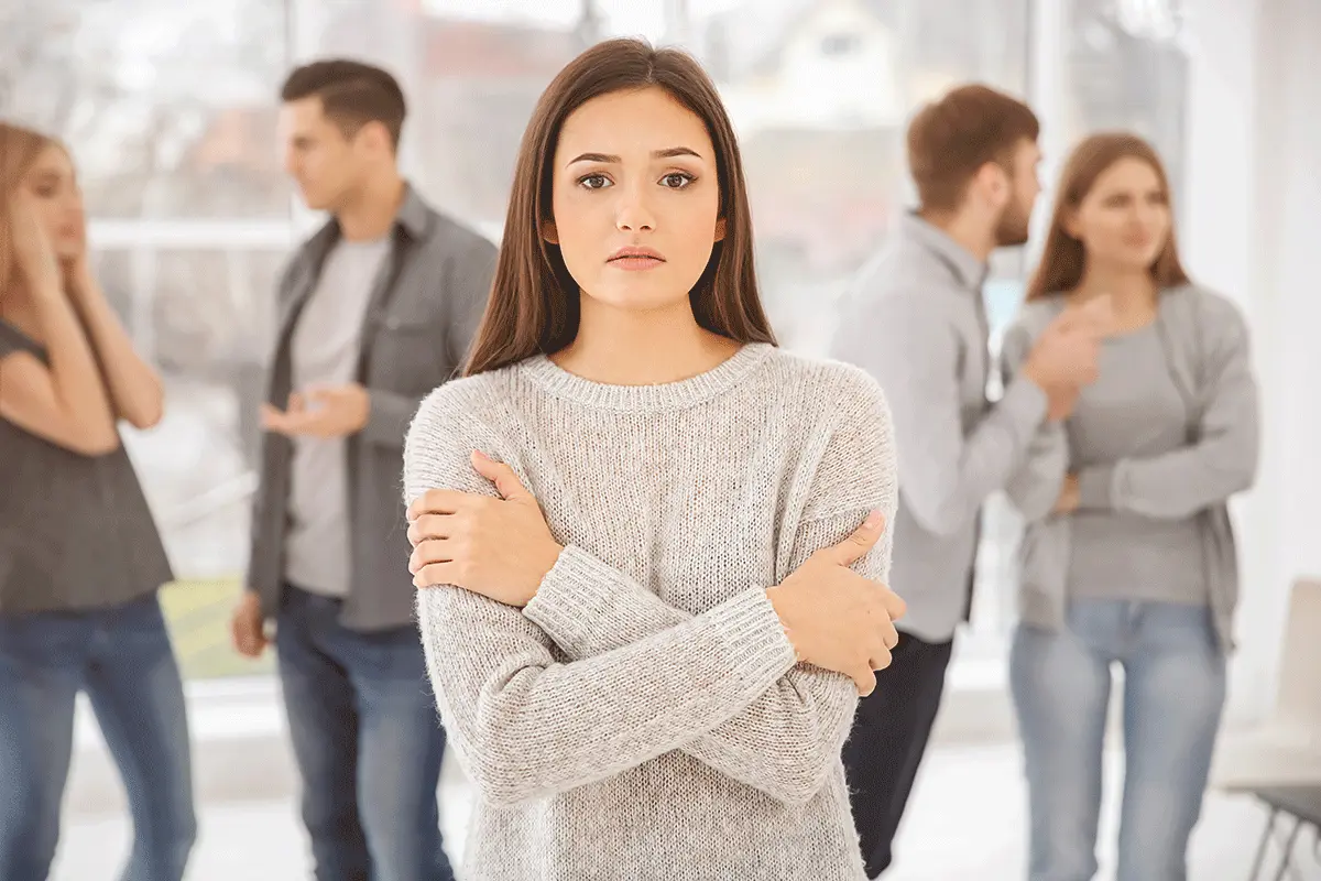 Young woman experiencing symptoms of social anxiety while standing apart from a group, representing professional social anxiety management and anxiety counseling services in Lahore.